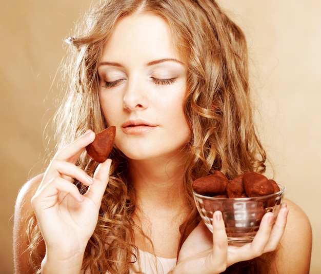 Chica rubia en acto de comer un caramelo de chocolate