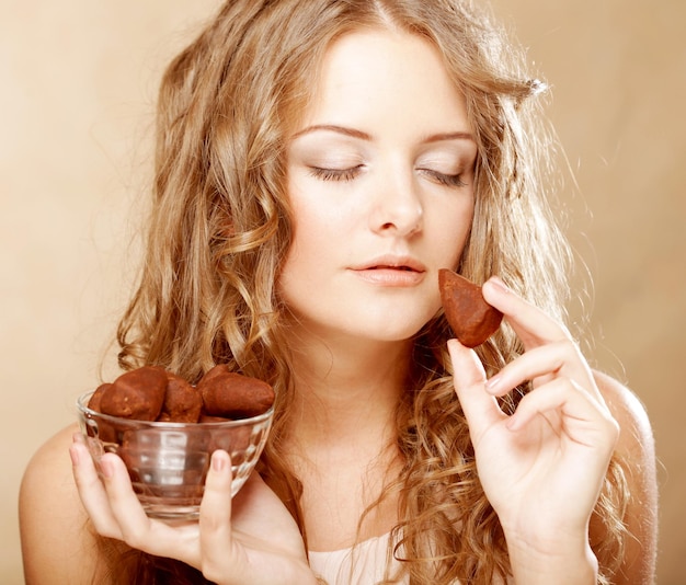 Chica rubia en acto de comer un caramelo de chocolate