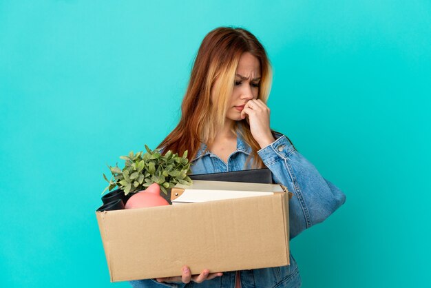 Chica rubia adolescente haciendo un movimiento mientras recoge una caja llena de cosas que tienen dudas