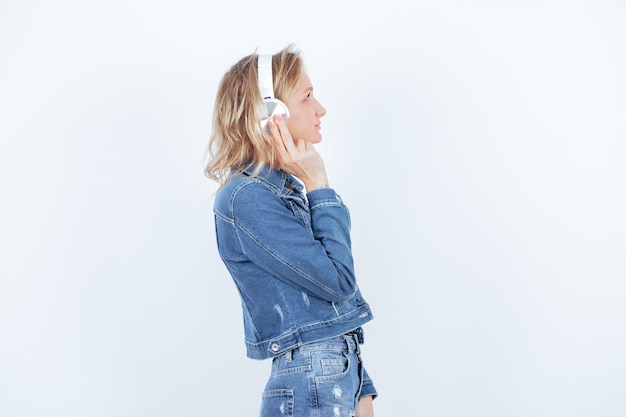 Chica rubia con auriculares está girando a la derecha sobre fondo blanco.