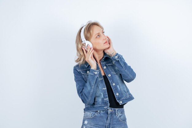 Chica rubia con auriculares está mirando hacia arriba sobre fondo blanco.