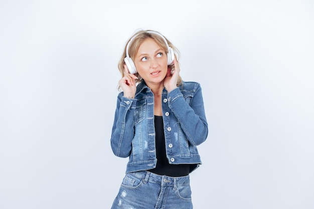 Chica rubia con auriculares está mirando hacia arriba sobre fondo blanco.