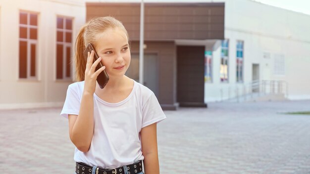 Chica rubia con cabello largo en cola de caballo habla en smartphone