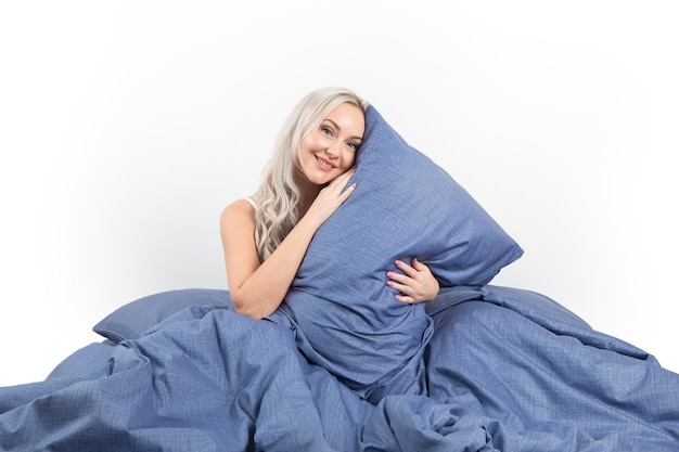 chica rubia en la cama con almohadas blancas y una manta en un dormitorio luminoso, textiles para el hogar