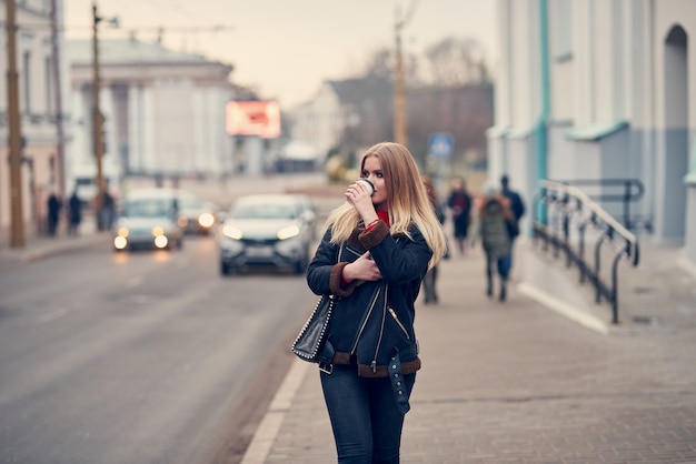 chica rubia camina por la ciudad y tomar un café