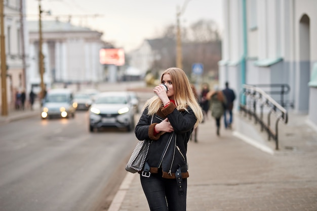 chica rubia camina por la ciudad y tomar un café