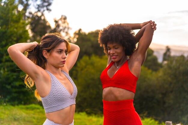 Chica rubia caucásica y chica de piel oscura con cabello afro haciendo estiramientos