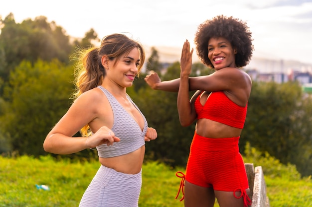 Chica rubia caucásica y chica de piel oscura con cabello afro haciendo estiramientos