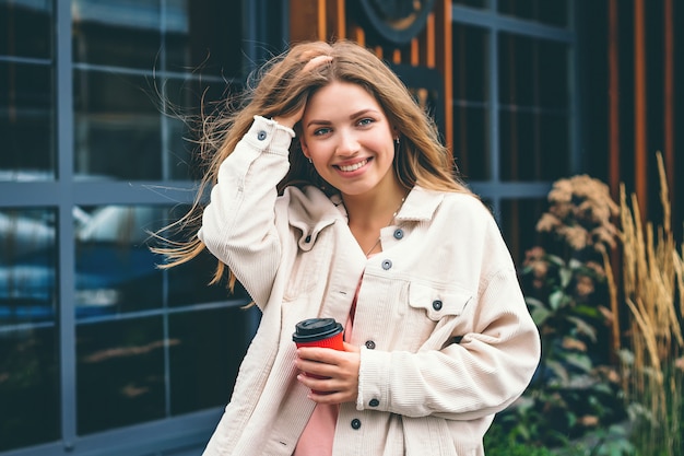 Chica rubia chica estudiante sonríe y camina por la ciudad y se para