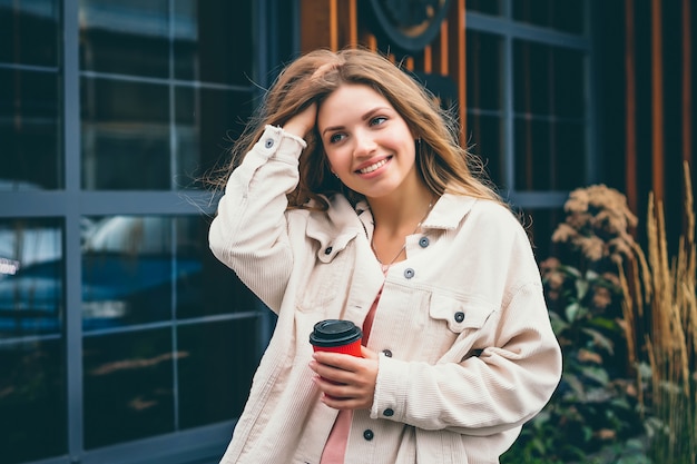 Chica rubia chica estudiante sonríe y camina por la ciudad y se para