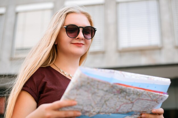 Chica rubia en la ciudad europea con un viaje en verano