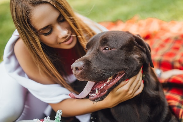 Foto chica rubia descansando con perro en el parque