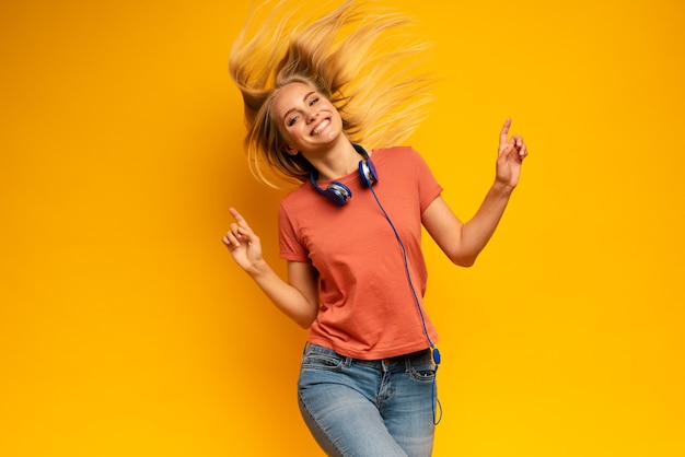 Foto chica rubia escucha música con auriculares