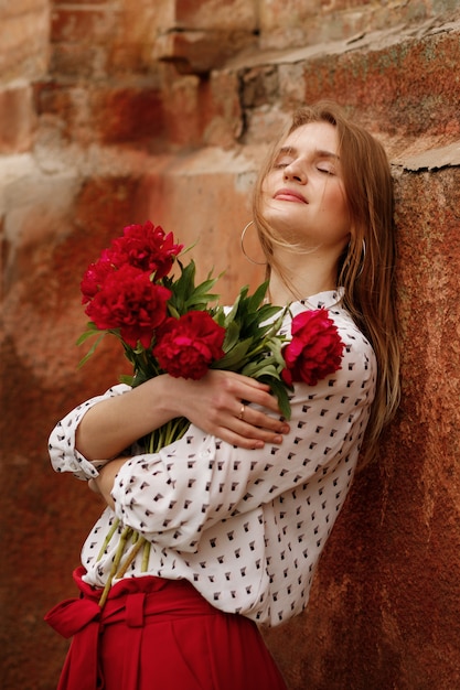 Chica rubia con flores rojas en un paseo por la ciudad