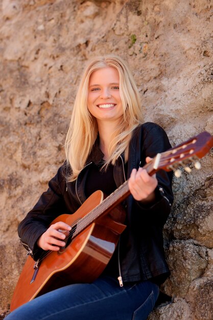 Chica rubia fresca tocando la guitarra al aire libre