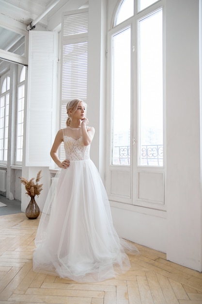 Chica rubia en un hermoso vestido de novia blanco.