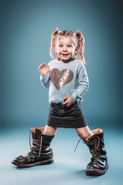 Chica rubia juega con botas grandes