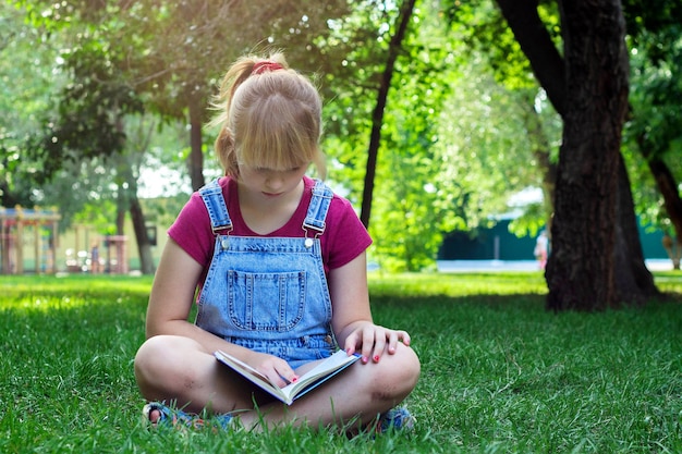 Chica rubia con libro sobre hierba verde