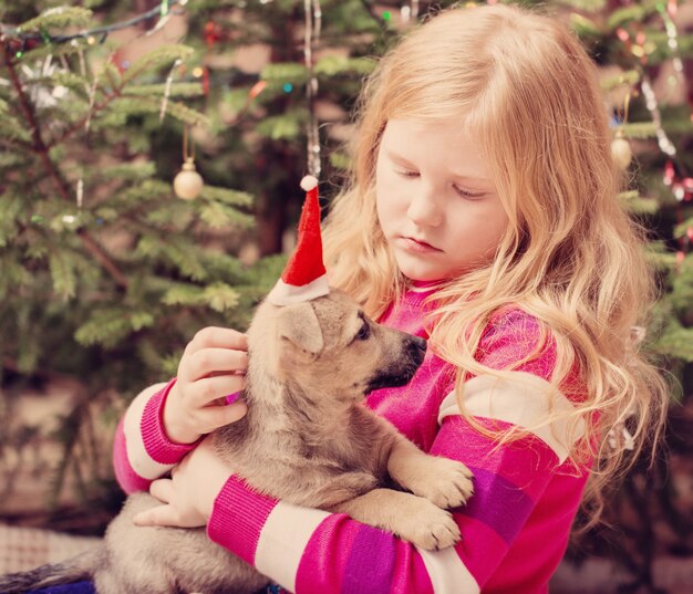 Chica rubia con littledog en rojo sombrero de navidad