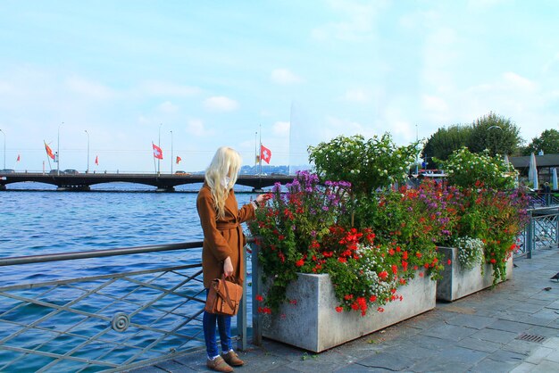 Chica rubia en la orilla del lago de Ginebra, cerca de las flores. Suiza