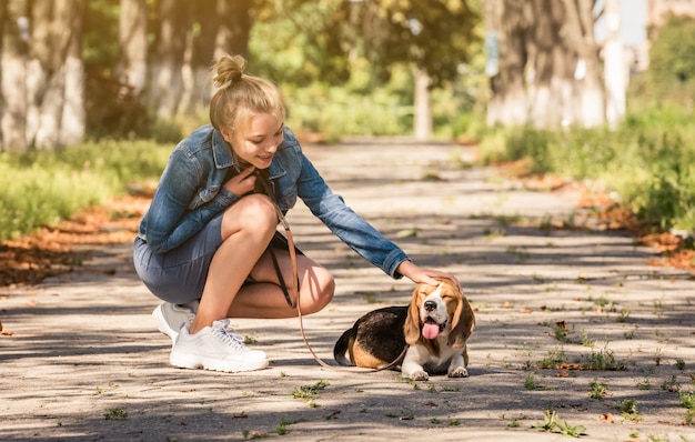 chica rubia sentada con perrito en un parque