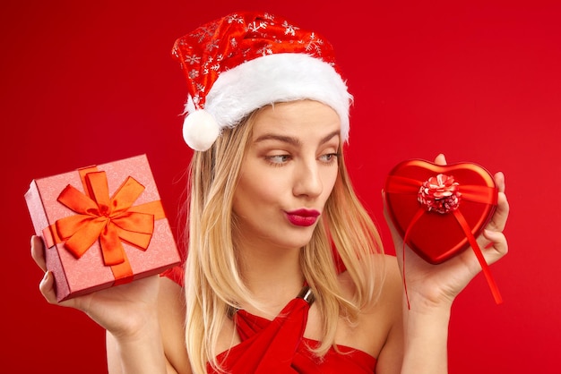 Chica rubia sexy con sombrero festivo de santa claus elige regalos de navidad para familiares y amigos. Descuentos y promociones de año nuevo, joven mujer de compras.