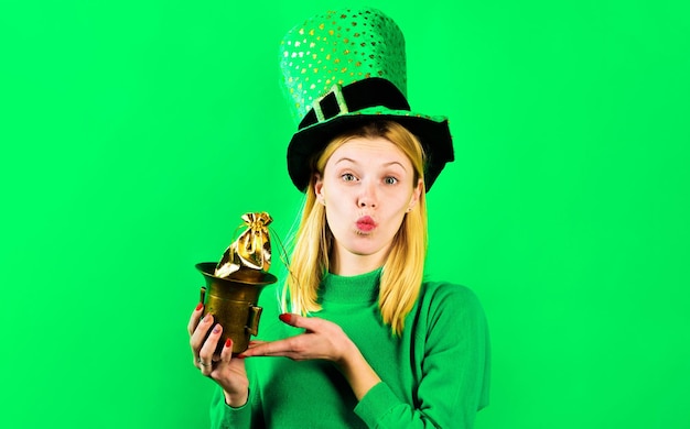 Chica rubia con sombrero verde con olla con oro y enviando beso tradiciones irlandesas del día de san patricio
