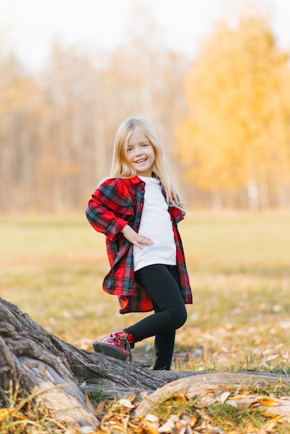 Chica rubia sonriendo en el parque otoño