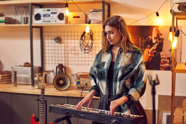 Chica rubia tocando el teclado en el estudio de grabación de música