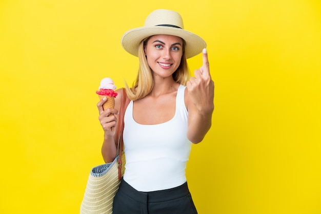 Chica rubia uruguaya en verano sosteniendo helado aislado en fondo amarillo haciendo gesto de venir