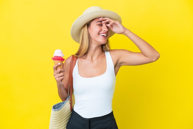 Foto chica rubia uruguaya en verano sosteniendo helado aislado sobre fondo amarillo sonriendo mucho