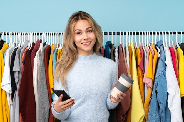 Chica rusa adolescente comprar algo de ropa aislado en azul