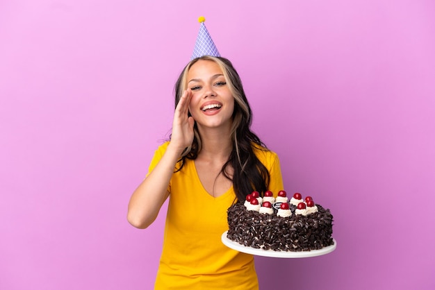 Chica rusa adolescente sosteniendo pastel de cumpleaños aislado sobre fondo púrpura gritando con la boca abierta