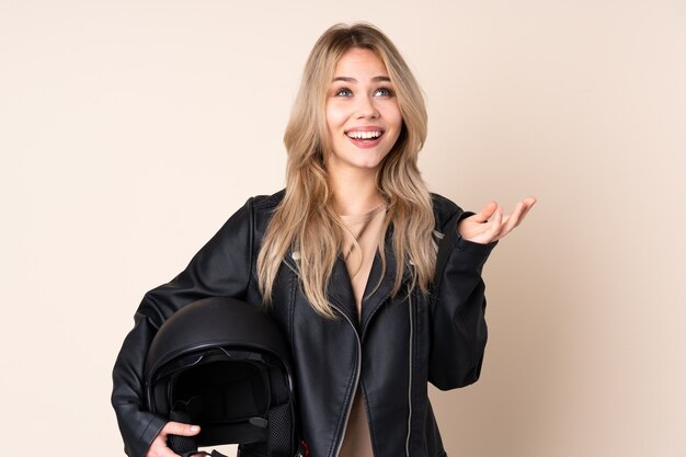 Chica rusa con un casco de moto aislado en beige sonriendo