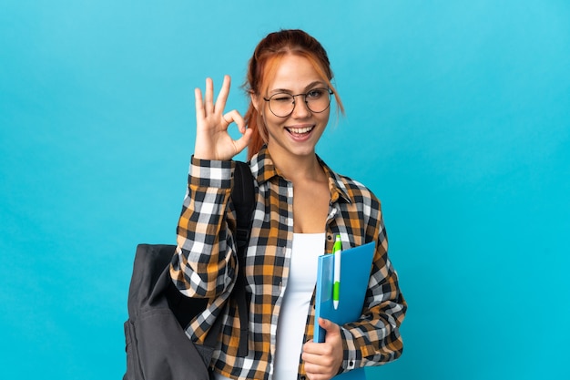 Chica rusa estudiante adolescente en azul mostrando signo ok con los dedos