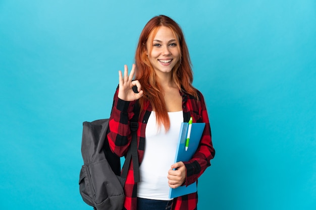 Chica rusa estudiante adolescente en azul mostrando signo ok con las dos manos