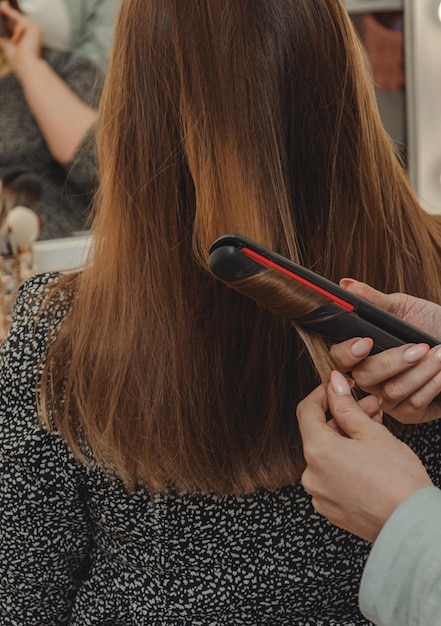 Chica en salón de belleza está peinando su cabello.