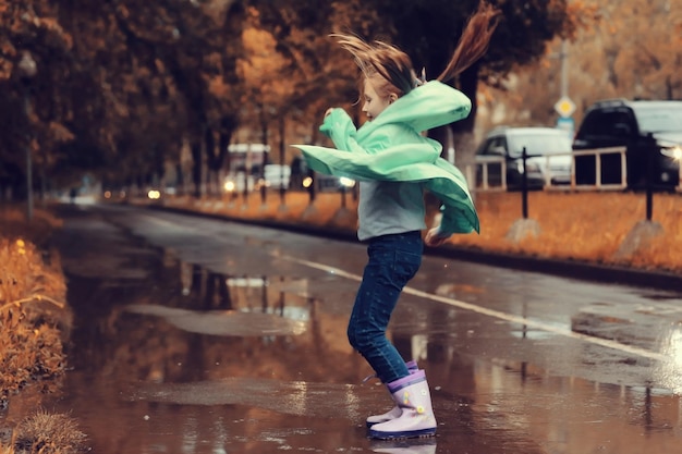 chica saltando en los charcos en la lluvia de otoño