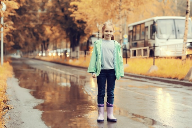 chica saltando en los charcos en la lluvia de otoño