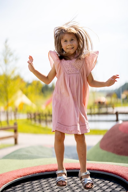 Chica saltando en un trampolín inflable en el parque de diversiones