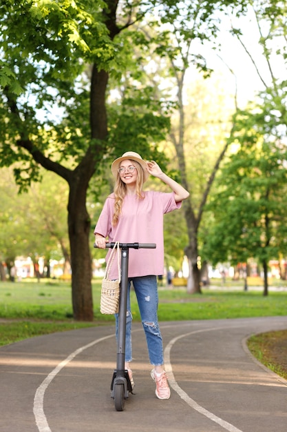 Chica en un scooter en el parque en verano en un paseo