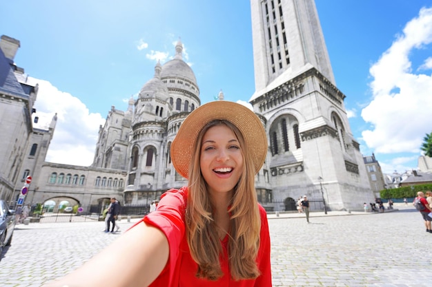 Chica selfie en París con la Basílica del Sagrado Corazón de París al fondo Sonriendo a la cámara Ángulo bajo