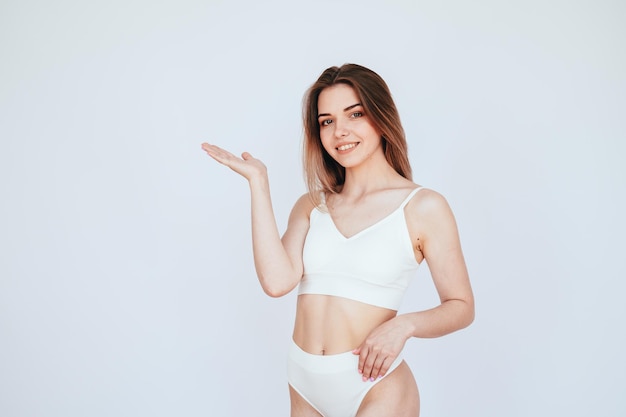 Chica señala su mano a un espacio vacío en concepto de ropa interior blanca de cuidado del cuerpo y salud de la mujer