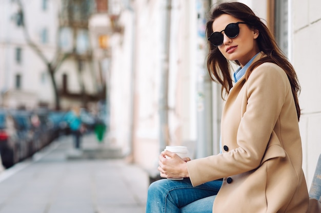 Chica sentada en el banco y tomando café