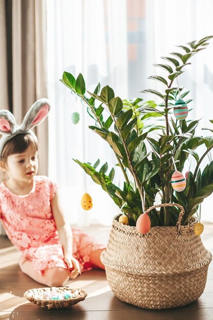 Chica sentada cerca de la planta de la casa decorada con huevos de Pascua