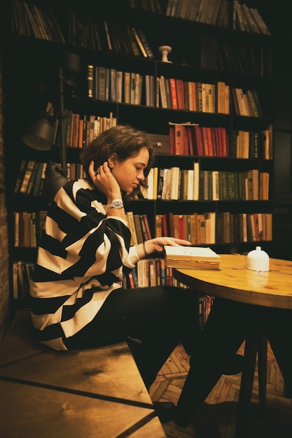 Chica sentada con un libro y una taza de café en la cafetería.