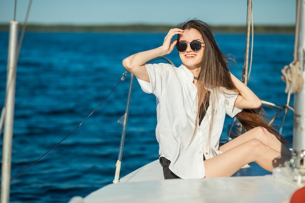 Chica sentada en la proa de un barco de vela
