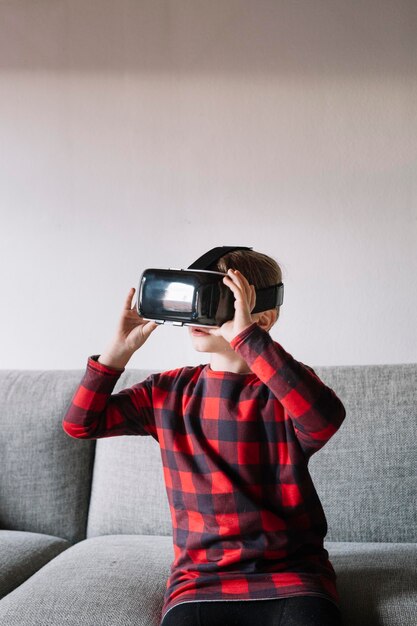 Chica sentada en el sofá de la sala de estar usando gafas de realidad virtual