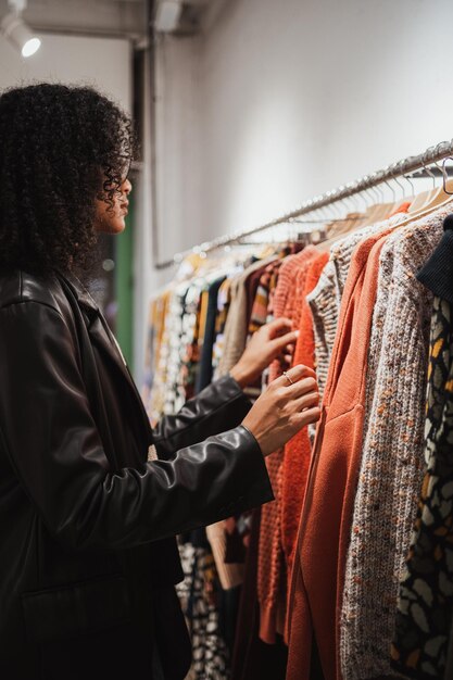 Chica seria eligiendo qué suéter comprar en una tienda para el invierno Ella es pensativa