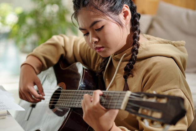 Chica seria tocando la guitarra